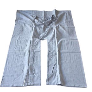 May include: Light blue Thai fisherman pants made of soft fabric. These wide-leg pants feature a wrap-around design with a tie closure at the waist. The pants have a relaxed fit and are suitable for casual wear. The pants are approximately 40 inches long.