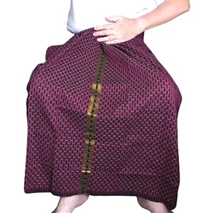 以下が含まれることがあります： 金色の縁取りのある紫と金色の模様の入ったスカート。スカートは座っている人が着用しています。