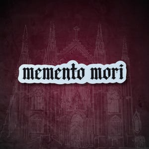 K&ouml;nnte beinhalten: Ein wei&szlig;er Aufkleber mit den Worten "memento mori" in gotischer Schrift. Der Aufkleber befindet sich auf einem weinroten Hintergrund mit einer wei&szlig;en Strichzeichnung einer Kathedrale.