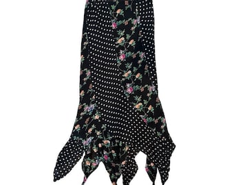 Può includere: Una gonna midi dal design a motivi misti, caratterizzata da pannelli in tessuto nero con pois bianchi e pannelli neri decorati con una stampa floreale di fiori rosa, arancioni e blu su steli verdi, rifinita con un orlo asimmetrico.