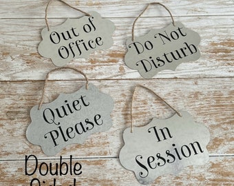 May include: Four double-sided signs with hanging twine. The signs are made of metal with a distressed white finish and black lettering. The signs read "Out of Office", "Do Not Disturb", "Quiet Please", and "In Session".