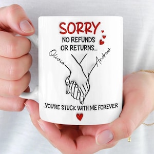 May include: White ceramic mug with the text "SORRY, NO REFUNDS OR RETURNS... YOU'RE STUCK WITH ME FOREVER." The mug features a graphic of two hands holding each other, with the names "Olivia" and "Andrew" written on either side. Red hearts accent the design.