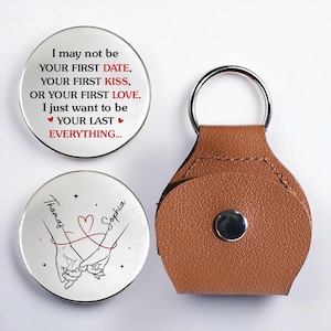 May include: A set of personalized keychains with a brown leather holder. One keychain has the text "I may not be your first date..." and the other has the names "Thomas" and "Sophia" with a heart and hands illustration.