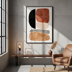 Op de afbeelding: Abstracte kunstprint met geometrische vormen in zwart, roest, beige en grijs. Het kunstwerk is ingelijst in zwart en hangt aan een betonnen muur. Een moderne lamp, houten bank en leren fauteuil maken het interieur compleet.