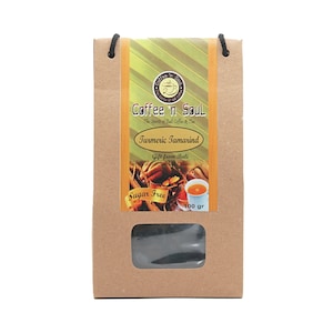 Pode incluir: Um saco de papel castanho com uma janela que mostra um saquinho de chá preto. O saco tem um rótulo com o texto "Coffee n Soul", "The Spirits of Bali Coffee & Tea", "Turmeric Tamarind", "Gift from Bali", "Sugar Free" e "100 gr".