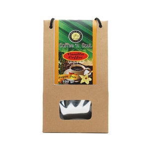 Puede incluir: Una bolsa de papel marrón con asas de cuerda negra y una ventana transparente rectangular. La etiqueta presenta el texto Coffee 'n Soul, Vanilla Coffee, Gift from Bali y Sugar Free, con una taza de café y una flor de vainilla, marcado 100 gr.