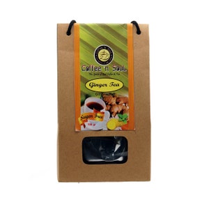 以下が含まれることがあります： コーヒー'nソウルとジンジャーティーと書かれた白いラベルが付いた茶色の紙袋。ラベルには「マリからの贈り物」と「砂糖不使用」の文字も書かれている。袋の中には100グラムのジンジャーティーが入っている。