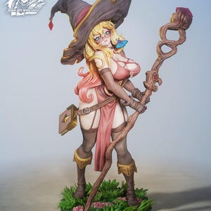May include: A detailed figurine of a female character, "Ruby the Gem Witch", with blonde hair, glasses, and a witch hat. She wears a pink outfit and holds a staff. The base is green with flowers. Text includes "3D Printable Pinup by Ronin Arts Workshop".