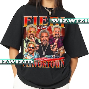 Op de afbeelding: Zwart T-shirt met een grafische print van drie mannen met de tekst "Fiery Guy Flavortown" en "WIZWIZID" op de voorkant.