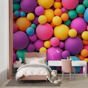 May include: A bedroom with a colorful wall mural of 3D spheres in shades of purple, pink, yellow, orange, teal, and blue. The room features a pink bed, a white desk, a pink chair, and a teddy bear.