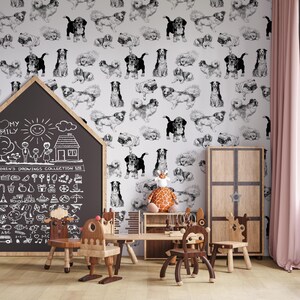 May include: A white wall with a black and white dog pattern wallpaper. The wall is decorated with a chalkboard with a drawing of a family and a house. There are wooden children's chairs and a table with a giraffe toy on it.