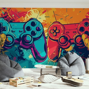 Puede incluir: Un mural vibrante con dos mandos de videojuegos estilizados en verde azulado y rojo sobre un fondo abstracto colorido. Los mandos son el punto focal, con un efecto de salpicaduras de pintura. La habitación incluye pufs y una guitarra.