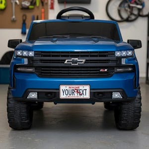 Könnte beinhalten: Ein blaues Spielzeug-Truck mit schwarzem Kühlergrill, Scheinwerfern und einem Nummernschild mit der Aufschrift "YOUR TEXT". Der Spielzeug-Truck hat große schwarze Reifen und ein schwarzes Lenkrad. Der Truck ist eine Miniaturversion eines Full-Size-Pickups.
