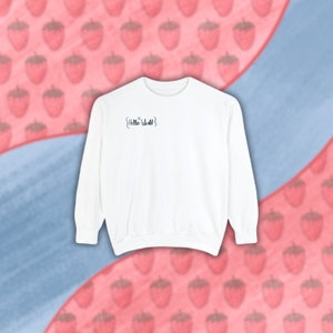 Op de afbeelding: Witte longsleeve trui met de tekst "{Hello World}" in blauw op de voorkant.