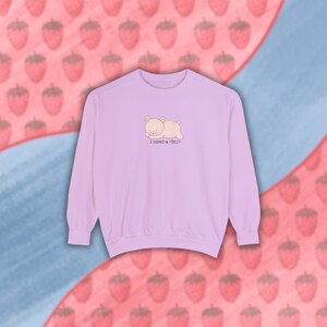 May include: A lavender sweatshirt with a cartoon pig sleeping on it. The text "I need a nap" is printed below the pig.