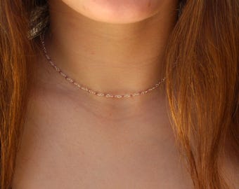 May include: A delicate gold chain choker necklace. The chain is thin and features a delicate, linked design.
