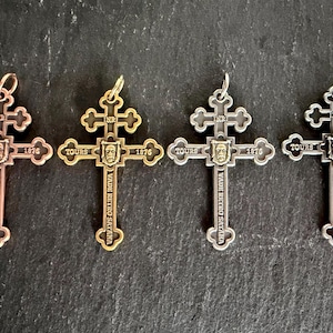 May include: Four metal cross pendants in copper, gold, silver, and dark gray tones. Each cross features the text INRI, TOURS, 1876, and VADE RETRO SATANA, with a central face relief. Each pendant includes a small circular loop at the top for hanging.