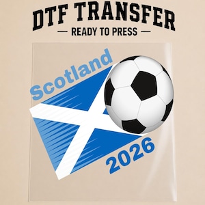 May include: A DTF transfer sheet featuring the text DTF TRANSFER READY TO PRESS at the top. Below, a graphic shows a blue and white Scottish flag, a black and white football, the word Scotland in blue, and the year 2026 in blue text.