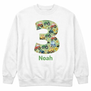 May include: White sweatshirt featuring a large number 3 filled with colorful cartoon tractors and construction vehicles on a green background. The name "Noah" is printed in green below the number.