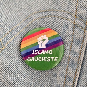 Peut inclure: Un bouton rond vert avec un motif arc-en-ciel et un poing blanc. Le texte "ISLAMO GAUCHISTE" est imprimé en blanc. Le bouton est posé sur un fond en denim bleu clair.