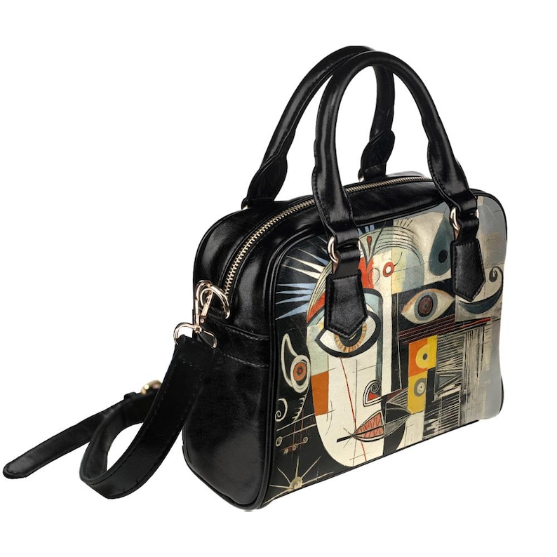May include: Black leather handbag with a colorful abstract art print. The bag features a top handle, a detachable shoulder strap, and a zipper closure. The artwork includes geometric shapes and facial features.