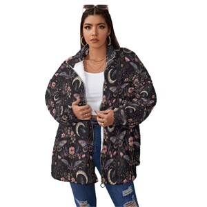 May include: A black zip-up jacket with a floral and celestial pattern featuring butterflies, moons, and flowers. The jacket has a white interior lining and a relaxed fit. The design includes shades of pink, purple, and cream.