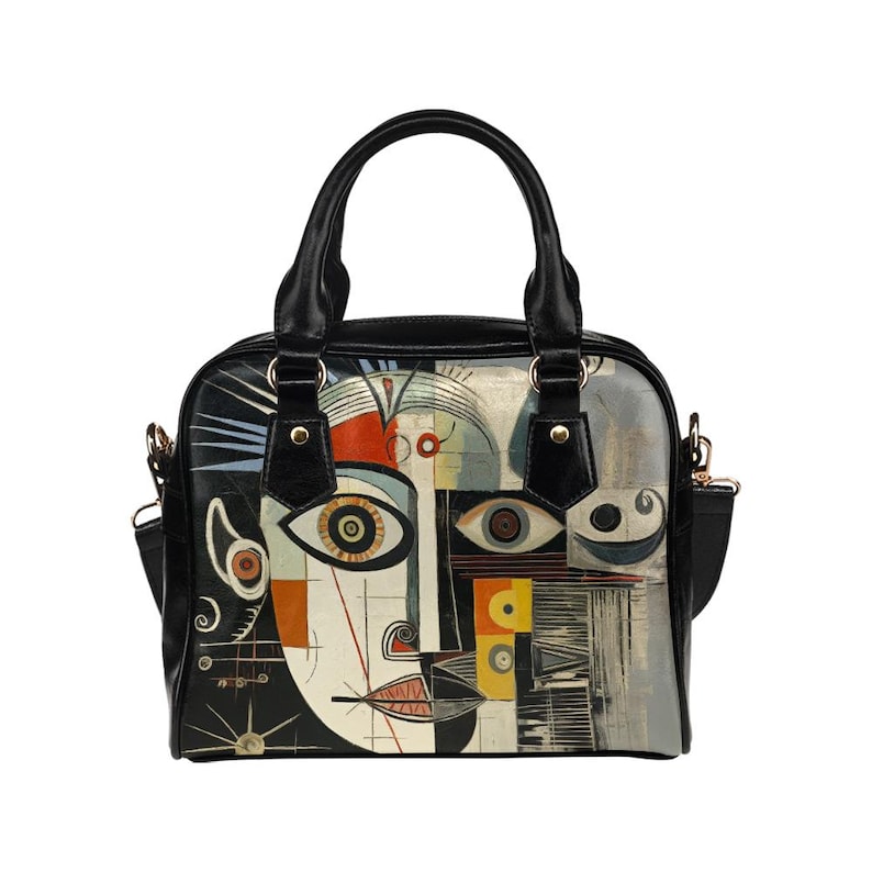 May include: Black and white handbag with a colorful abstract face design. The bag features a top handle and a detachable shoulder strap. The artwork includes geometric shapes, eyes, and a mouth, with accents of red, yellow, and orange.