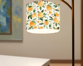 Peut inclure: Un lampadaire doré avec un abat-jour blanc orné d'un motif aquarelle de tranches d'orange et de feuilles vertes.