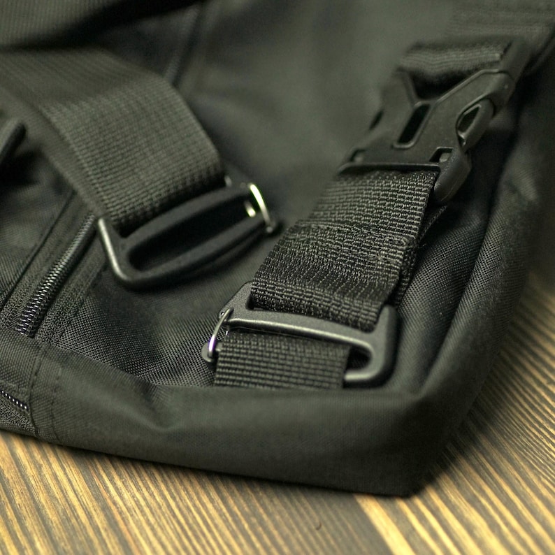 May include: Close-up of a black messenger bag with adjustable straps and a buckle closure.