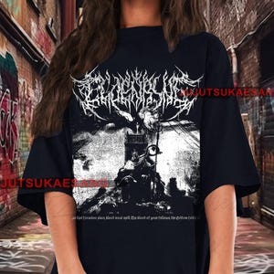 May include: Black t-shirt featuring a detailed black and white graphic design. The design includes ornate text and a dark, gothic illustration of a figure on a throne. The text on the shirt reads "JUTSUKAESAN" and a quote.