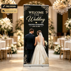 May include: A black wedding welcome sign with gold lettering and floral accents. The sign reads "WELCOME TO OUR Wedding" with the names Olivia & Daniel and the date June 15, 2025. A couple is pictured on the sign.