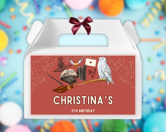 May include: White favor box with a red and gold Harry Potter themed design. The box has a handle and a red bow. The design includes a broom, a hat, a book, a snowy owl, and the text "Christina's 5th Birthday".