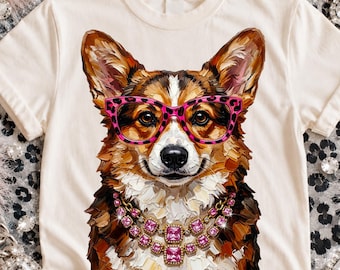 May include: A cream-coloured t-shirt featuring a painterly illustration of a Corgi dog. The dog wears bright pink leopard-print glasses and a multi-layered necklace made of square pink gemstones. The artwork uses visible, textured brushstrokes.