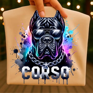 May include: A tan t-shirt featuring a graphic of a black Cane Corso dog wearing silver-rimmed sunglasses and a thick silver chain with a star pendant. The design includes vibrant blue and purple watercolor paint splatters and the word CORSO.