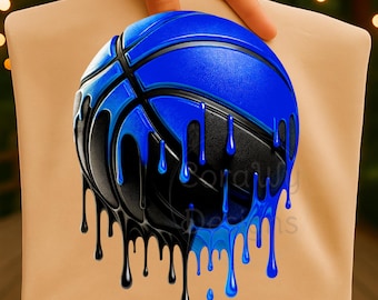 Puede incluir: Una camiseta de color tostado con un gráfico de un balón de baloncesto con efecto de pintura goteante. El balón es de color azul vibrante y negro, con gotas de líquido azules y negras que se extienden hacia abajo sobre la tela.