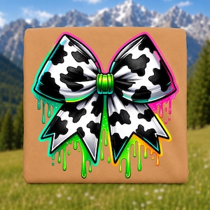 May include: A tan square fabric item featuring a large graphic of a bow with a black and white cow print pattern. The bow has a bright green center knot and is surrounded by vibrant neon-colored paint drips in shades of green, yellow, and pink.