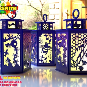 Puede incluir: Tres linternas hexagonales azules con intrincados diseños recortados que presentan abejas, flores y patrones de panal. Las linternas están iluminadas desde adentro, creando un brillo cálido. El texto "CustSmith .STL" es visible en la esquina superior izquierda de la imagen.