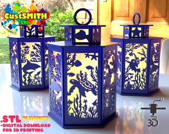Puede incluir: Tres faroles hexagonales azules con un diseño de vida marina. Los faroles tienen un diseño recortado de una tortuga, peces y algas marinas. Los faroles están iluminados desde el interior, creando un brillo cálido. El texto "CustSmith .STL" es visible en la esquina superior izquierda de la imagen. El texto "STL NO SUPPORTS - DIGITAL DOWNLOAD FOR 3D PRINTING" es visible en la esquina inferior izquierda de la imagen.
