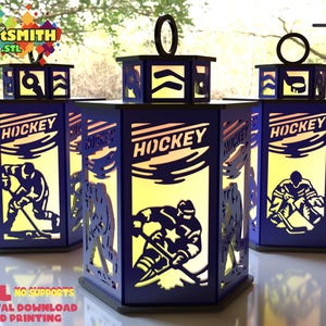 May include: Three navy blue hockey-themed lanterns with cut-out designs of hockey players and the word "HOCKEY". The lanterns have a warm, yellow glow from within. The top of each lantern has a handle. Text on the image reads ".STL NO SUPPORTS - DIGITAL DOWNLOAD FOR 3D PRINTING".