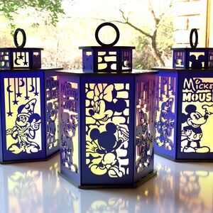 May include: Three blue and black lanterns with cut-out designs featuring Mickey Mouse and friends. The lanterns have a rectangular shape with a handle on top. The text "Mickey Mouse" is visible on one lantern.