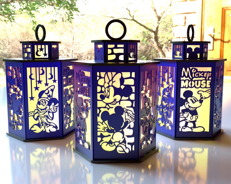 May include: Three blue and black lanterns with cut-out designs featuring Mickey Mouse and friends. The lanterns have a rectangular shape with a handle on top. The text "Mickey Mouse" is visible on one lantern.