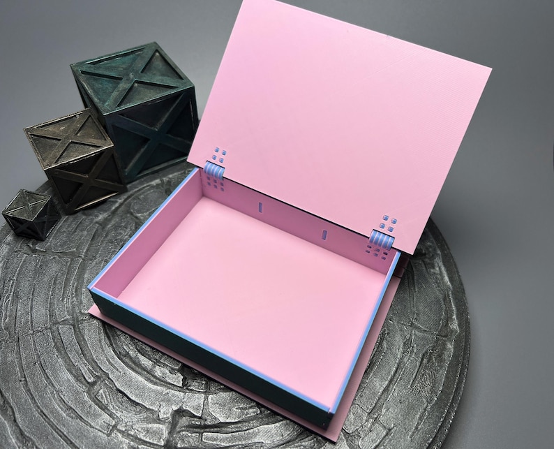 May include: A pink box with a teal border and a blue hinge. The box is open and the inside is pink.