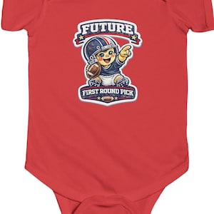 Puede incluir: Body de bebé rojo con un gráfico de un jugador de fútbol americano de dibujos animados sosteniendo un balón. El gráfico incluye el texto "FUTURE" y "FIRST ROUND PICK". El jugador lleva un casco y señala.