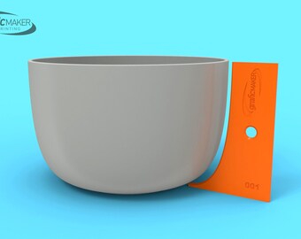 May include: A light gray, rounded bowl with an orange, curved tool next to it. The tool has a hole and the text "graficMAKER 3D PRINTING". The background is light blue.