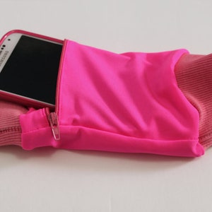 May include: A pink running armband with a zipped pocket to hold a phone. The phone is a Samsung Galaxy.