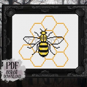 Puede incluir: Un patrón de punto de cruz con una abeja amarilla y negra con alas marrones, sentada en un panal.