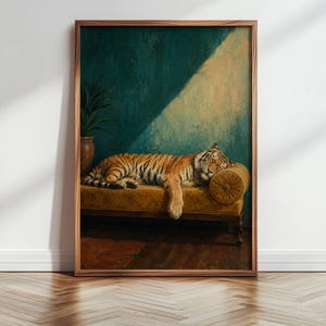 May include: A framed wall art print featuring an oil painting of a tiger resting on a mustard yellow velvet chaise lounge. The background is a deep teal wall with a diagonal beam of light. A potted plant sits to the left of the furniture.