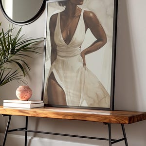 May include: A framed canvas print of a woman wearing a white dress. The woman is standing with her hand on her hip and looking to the side. The background is a light beige colour.
