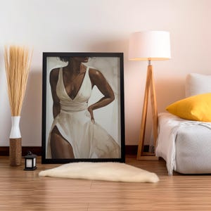 May include: A framed painting of a person wearing a white dress with a split up the side. The person has dark skin and is standing with one hand on their hip. The background is a light brown colour.
