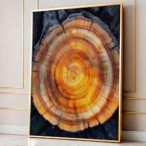 May include: A framed print featuring a close-up of a tree cross-section. The artwork showcases concentric rings in shades of orange, brown, and yellow, with a dark gray background. The print is encased in a gold frame, adding a touch of elegance to the natural subject.